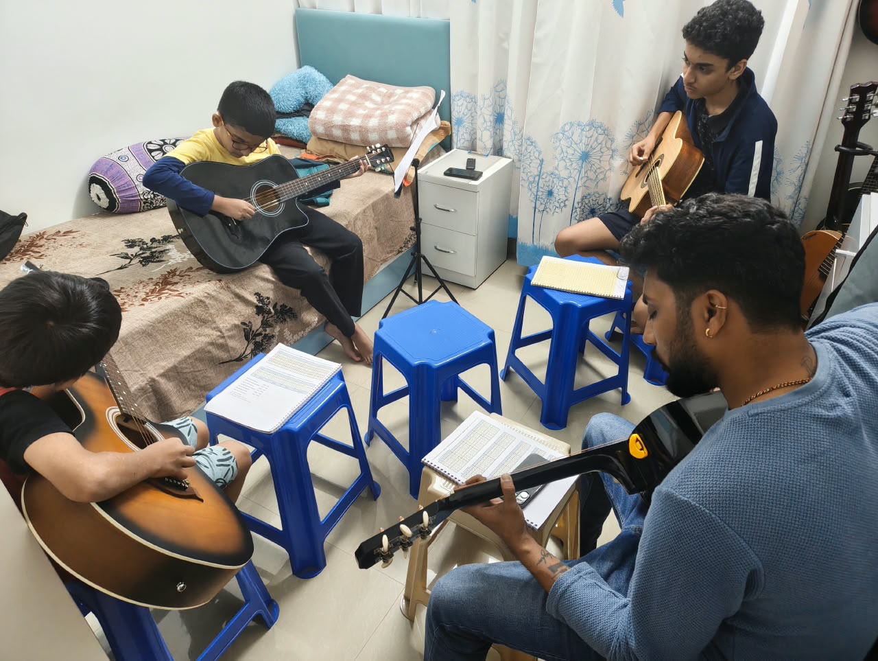 Students of different ages learning guitar together in a PKUNPLUGGED class